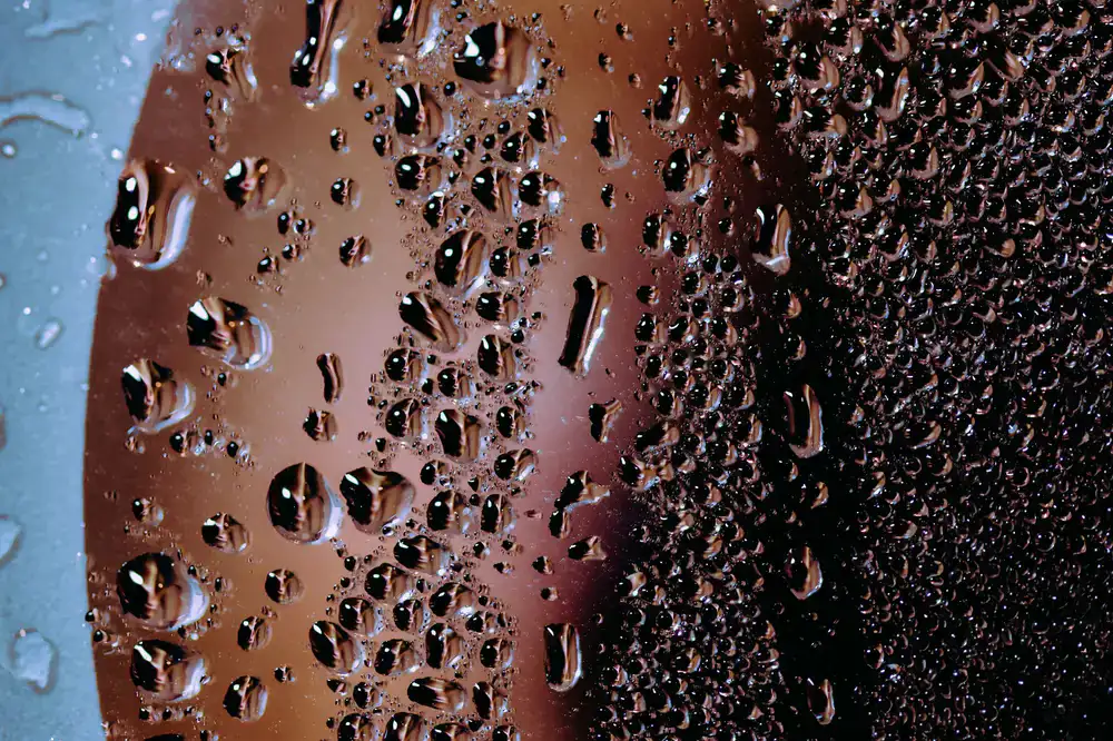 Close up view of condensation droplets on the inner curve of a glass vessel